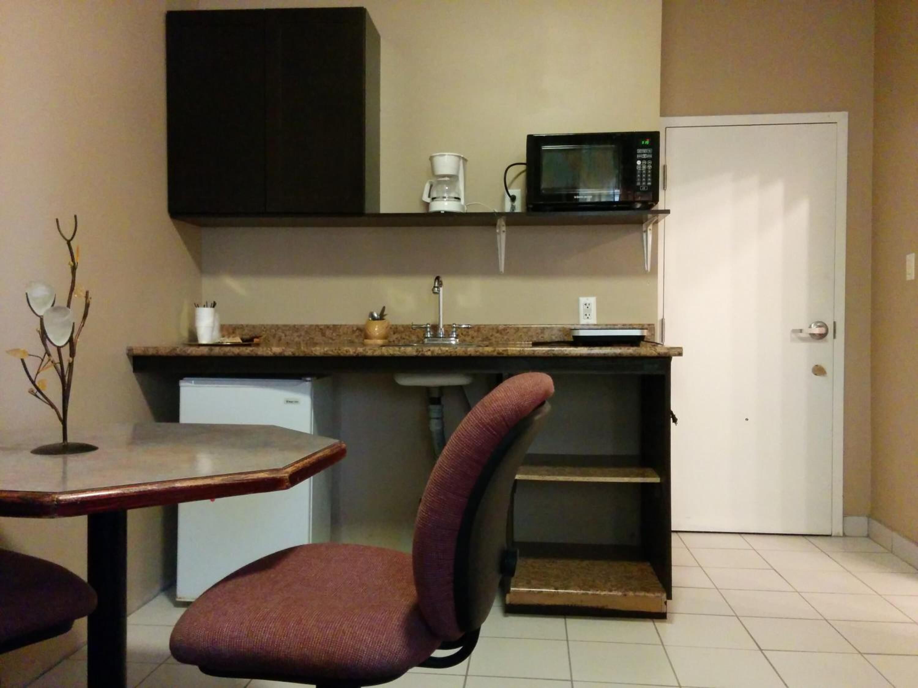 Una cocina compacta con microondas, cafetera y un refrigerador pequeño.