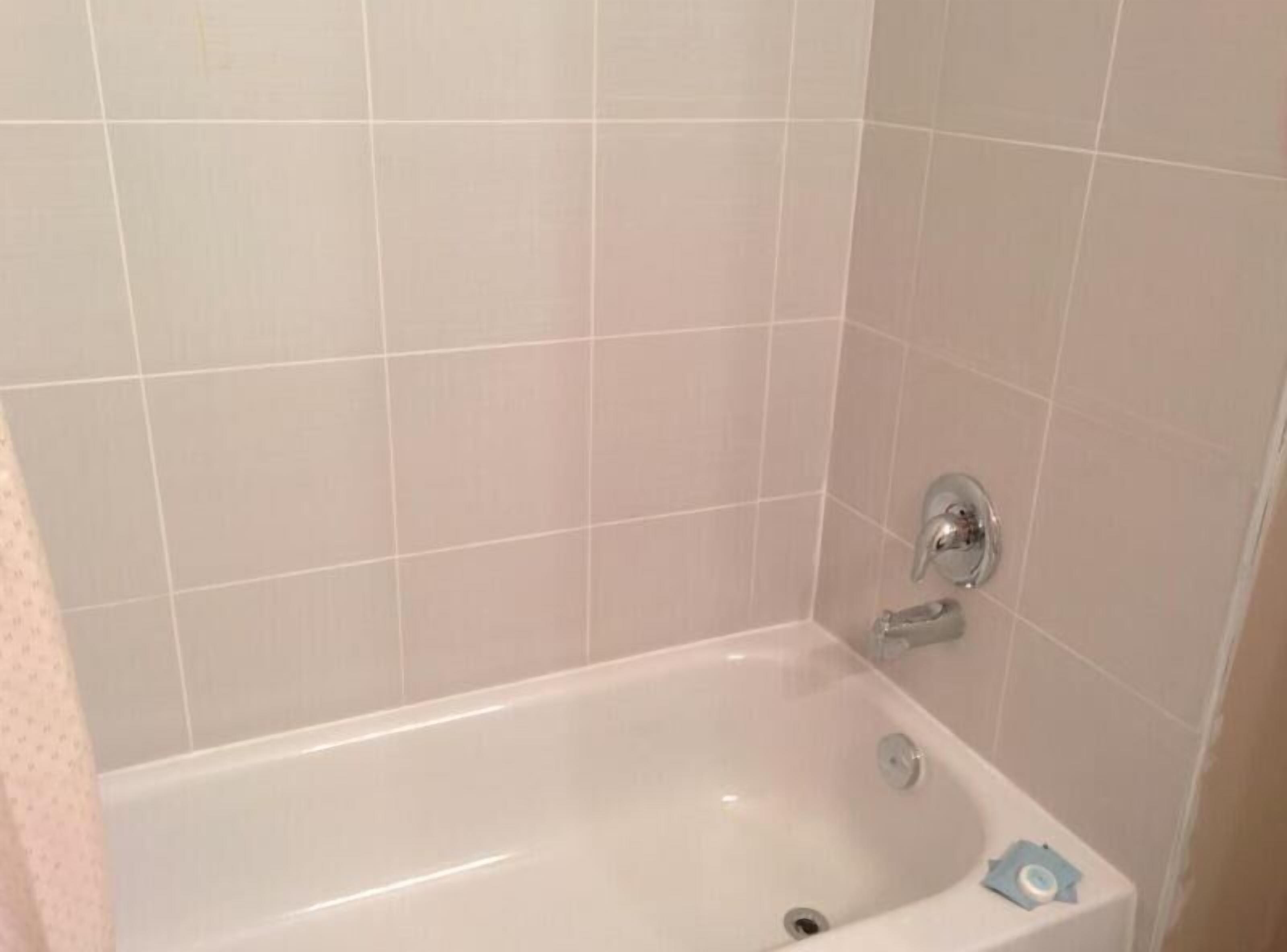 Un baño con una bañera blanca, un grifo y un cabezal de ducha.