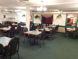 A dining area with multiple tables and chairs, a chandelier, and green walls.