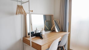 A compact hotel room with a wooden desk, a mirror, a chair, and a clothing rack. - Hongdae Lai Lai house (Seoul)