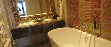 Un baño con una bañera grande, un tocador con espejo y azulejos con diseño.