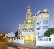 Um hotel de vários andares com uma torre do relógio imponente, varandas e uma entrada bem iluminada.