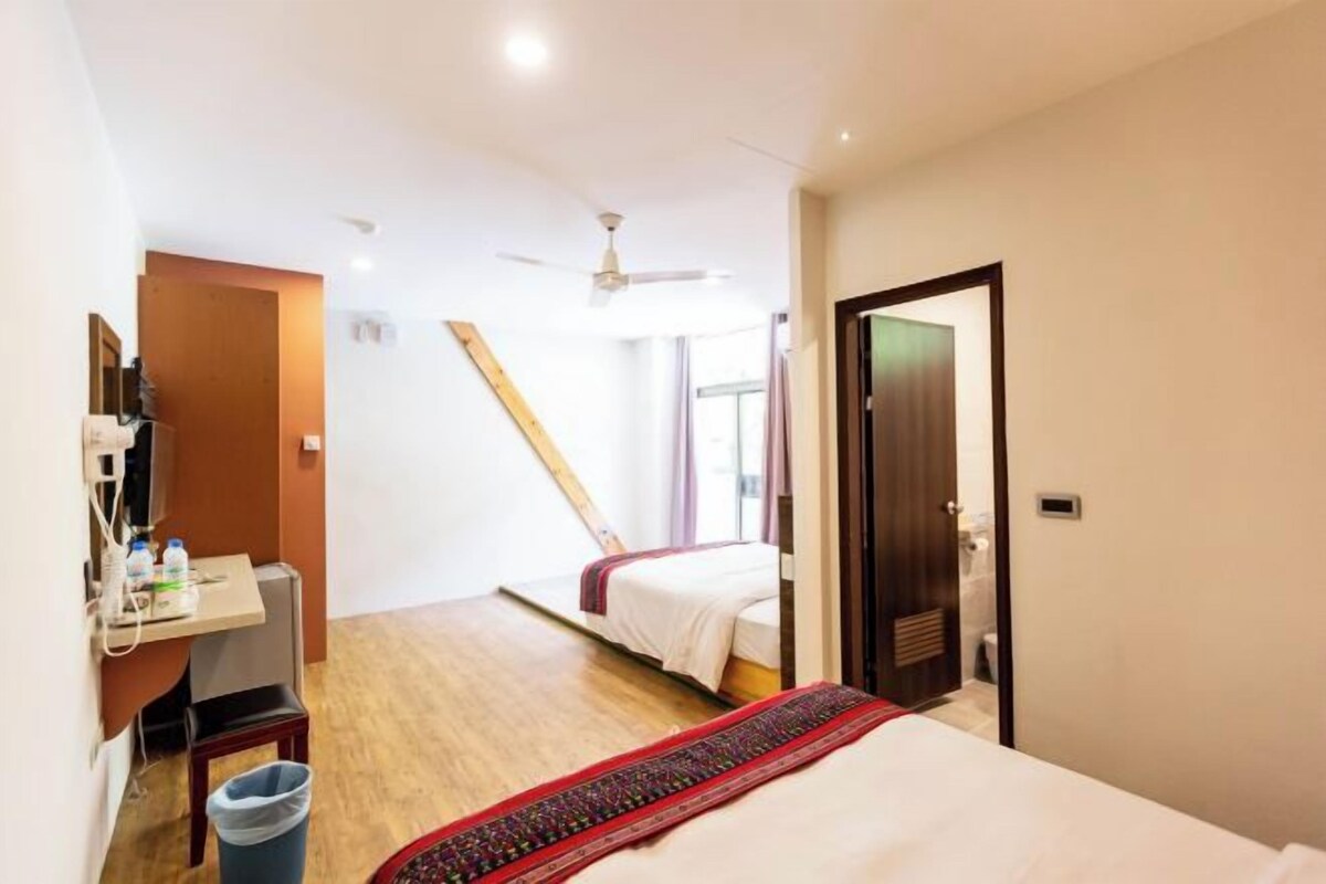 Ein Hotelzimmer mit Bett, Schreibtisch mit Stuhl, Mülleimer und Deckenventilator.
