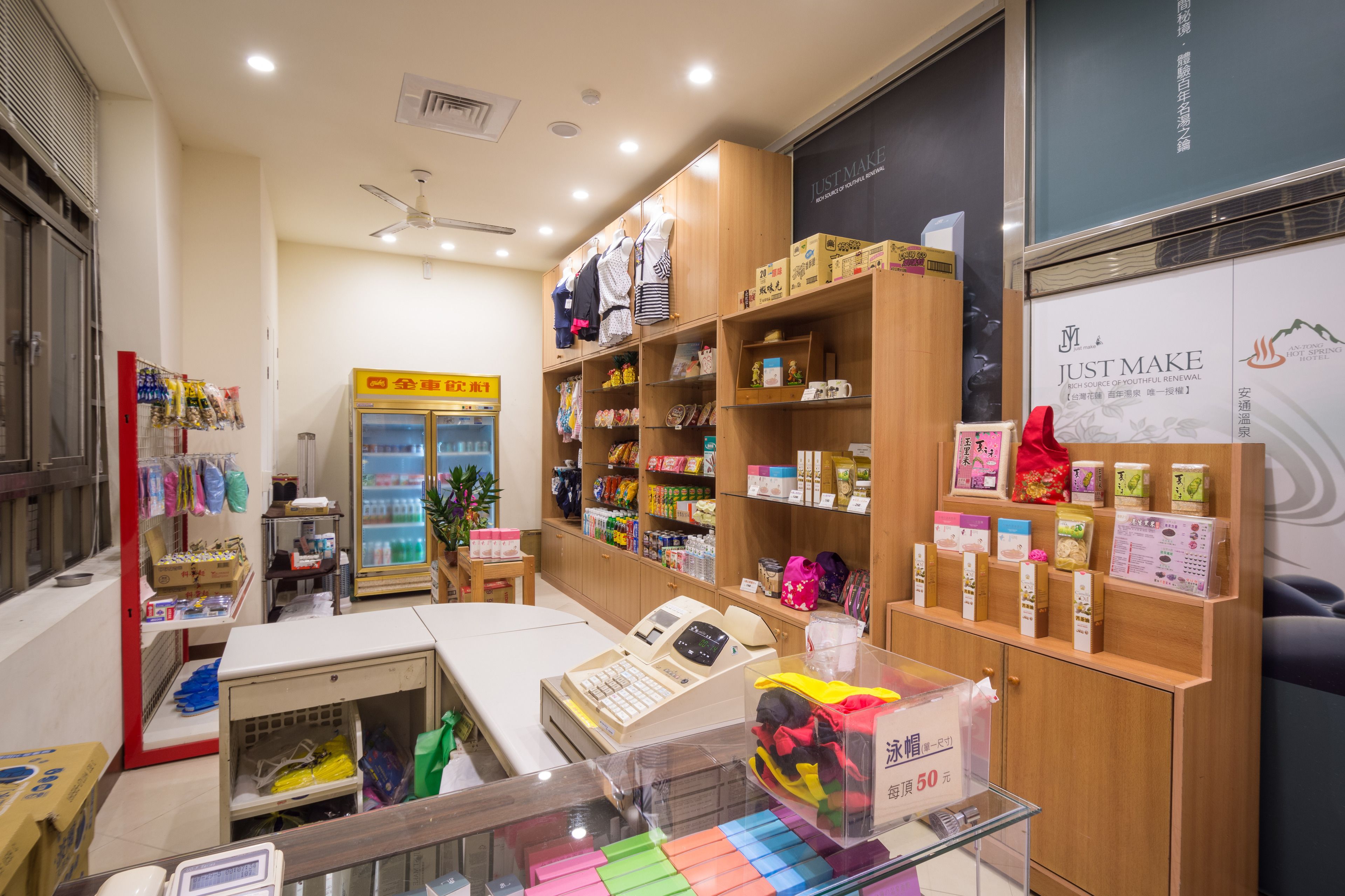 A store with shelves stocked with various products, a cash register, and a display case with colorful items.