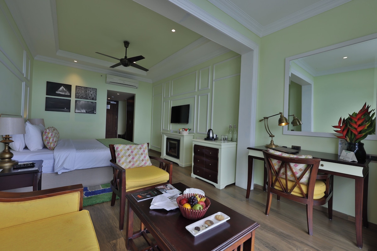 Una habitación de hotel con cama, escritorio, silla, mesa, televisor y ventilador de techo.