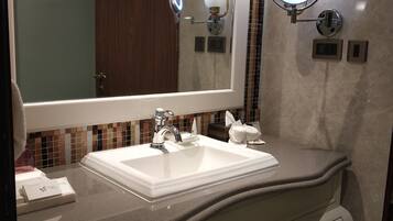 A bathroom with a large mirror, a white sink, and a vanity with drawers.