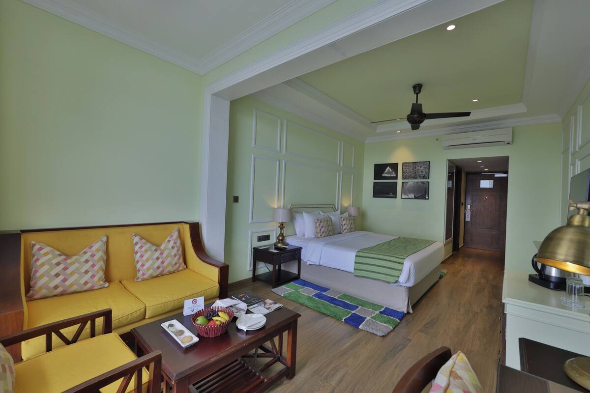 A hotel room with a bed, a sofa, a desk, and a dining table.