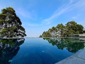 A clear pool with a reflection of trees and a clear sky. - Fragrant Nature Munnar - A Classified Hotel (Devikolam)