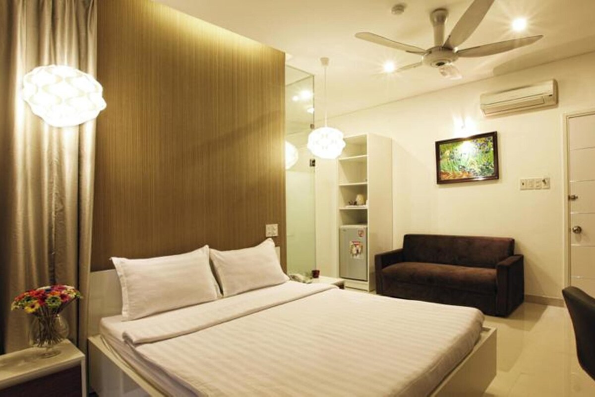Une chambre d’hôtel équipée d’un lit, d’un bureau, d’une chaise, d’un canapé, d’un ventilateur de plafond et d’un climatiseur fixé au mur.