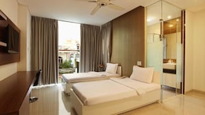 Une chambre d’hôtel avec deux lits, un bureau, une télévision et une vue sur la ville.