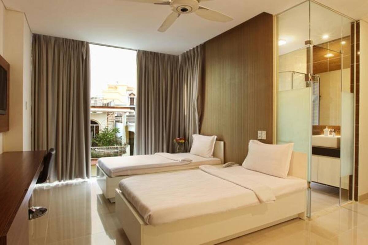 Habitación de hotel con dos camas, un escritorio, un televisor y vista a la ciudad.