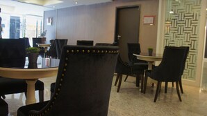 Un comedor moderno con sillas tapizadas negras, una mesa redonda y un diseño decorativo en la pared.
