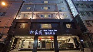 Un hotel con fachada moderna, varios pisos y señalización iluminada.