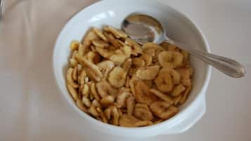 A white bowl filled with dried banana slices and a spoon.