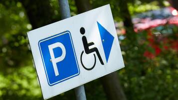 Ein Parkschild mit Rollstuhlsymbol und einem nach rechts zeigenden Pfeil.