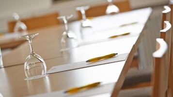 A conference room with tables, chairs, and empty wine glasses.