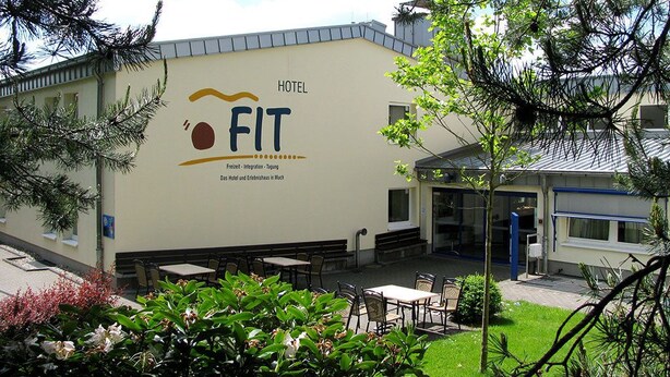 A hotel named "FIT" with outdoor seating and a garden area. - Hotel FIT (Much)