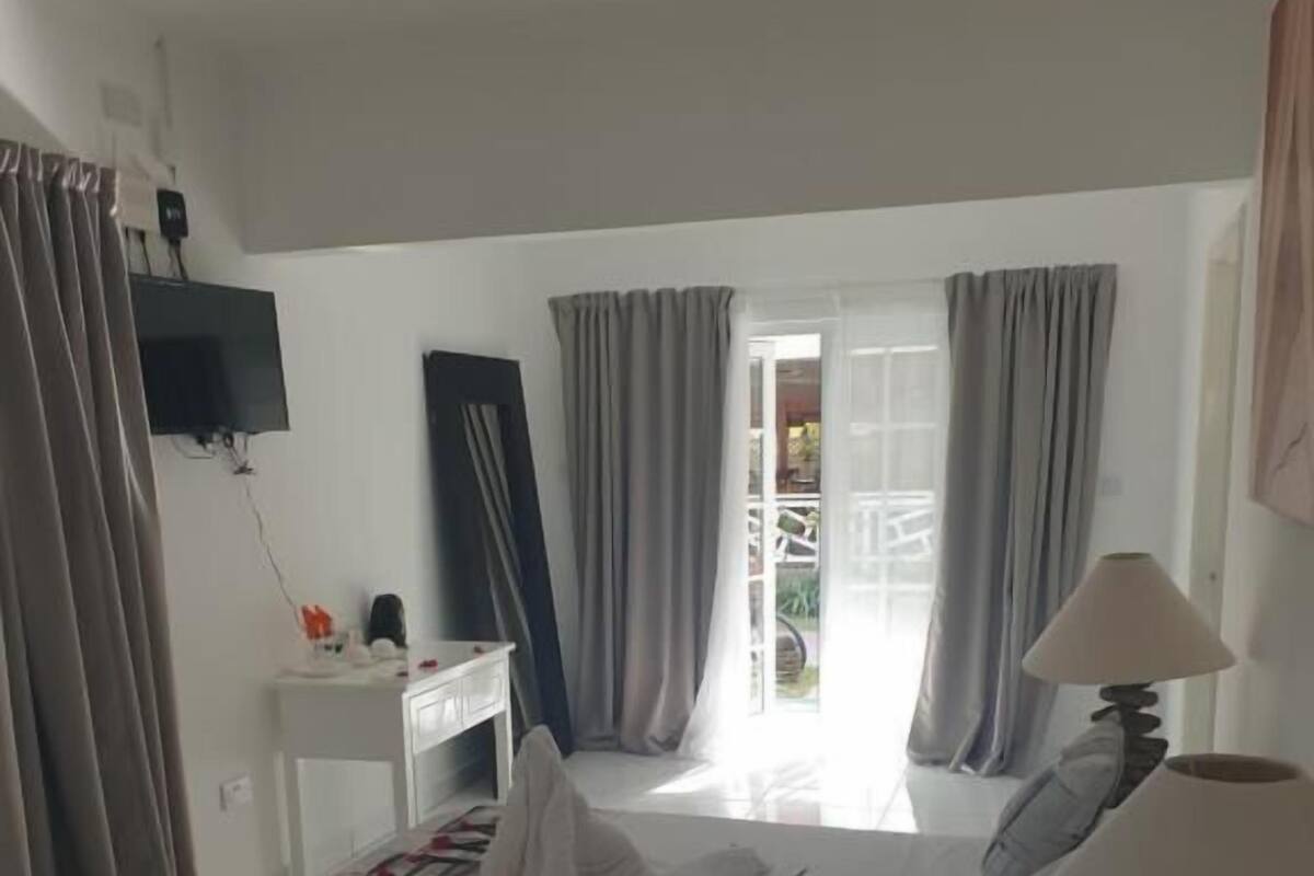 Quarto de hotel com cama, escrivaninha, televisão e vista para o exterior.