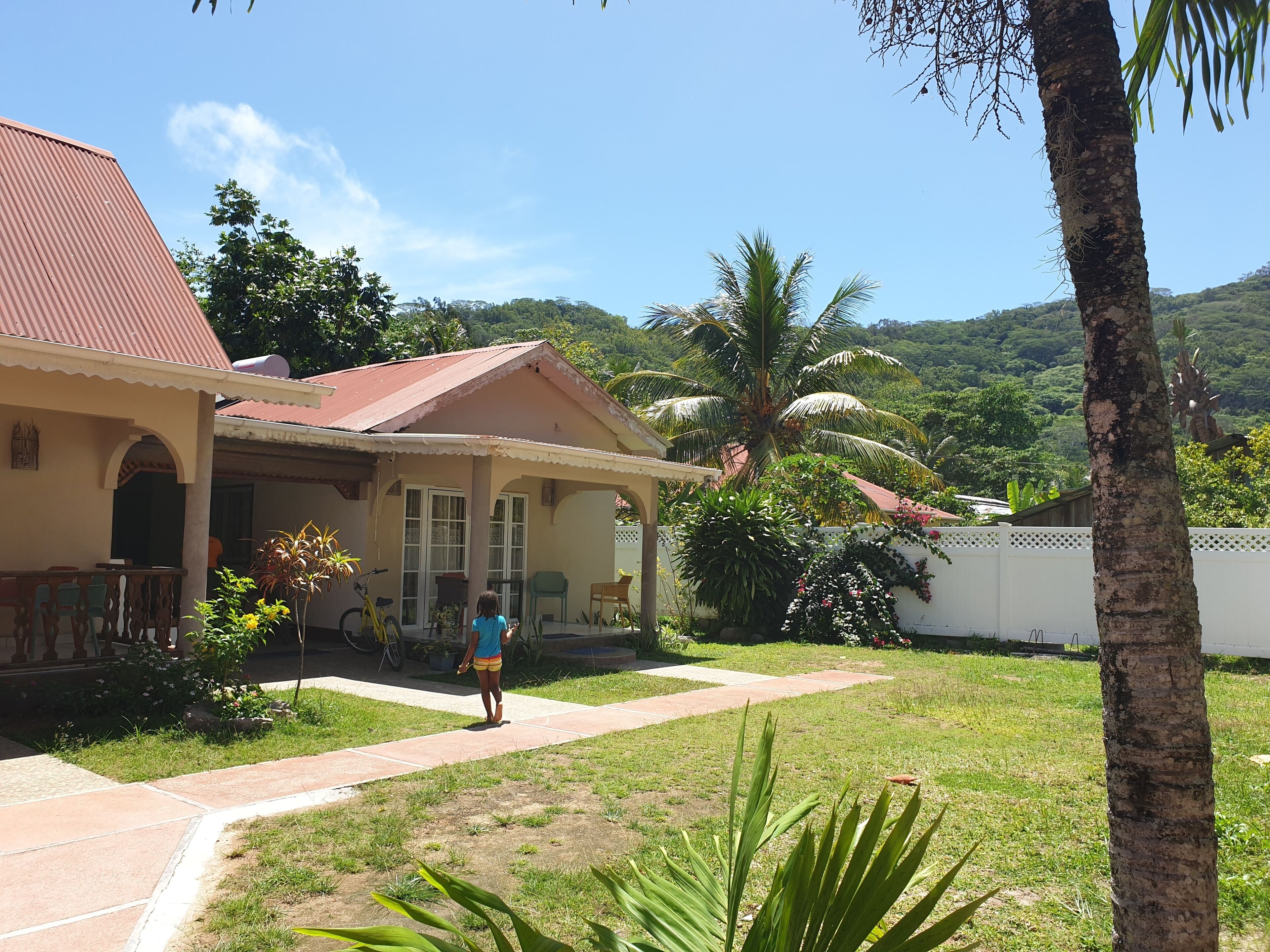 A house with a red roof, a covered porch, and a pathway leading to the entrance.