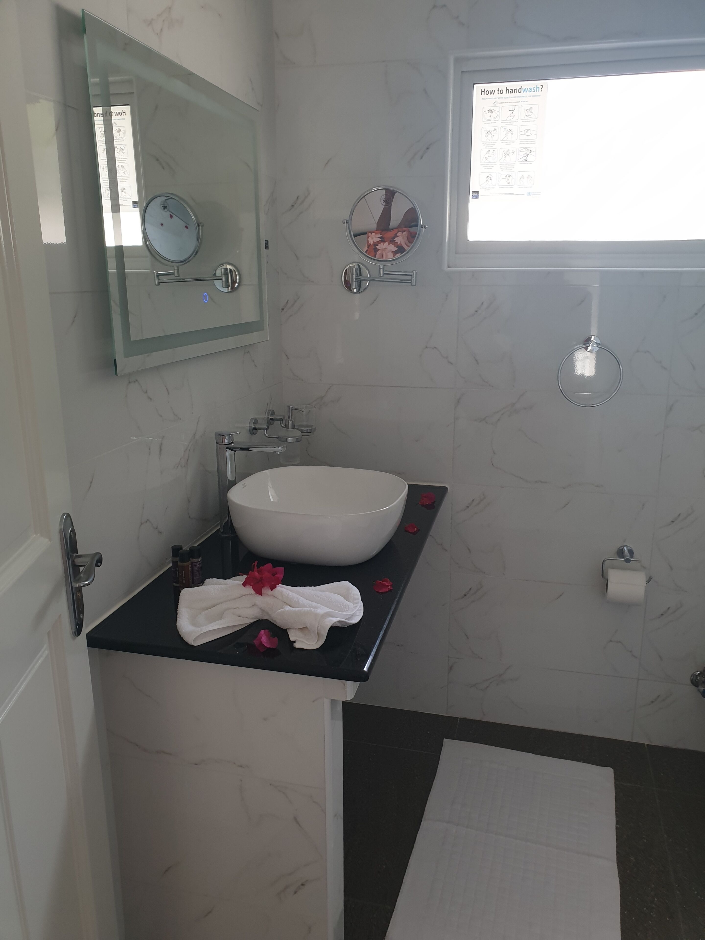 A bathroom with a white sink, a mirror, and a handwashing poster.