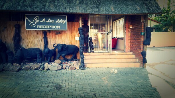 A reception area with a sign reading "Jo-A-Lize Lodge RECEPTION", a thatched roof, and a statue of a bull. - iLanga Lodge (St. Lucia)