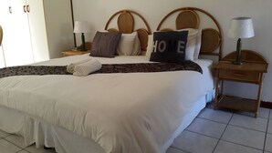 A neatly made bed with a 'HOME' pillow, a patterned throw, and a pair of folded towels. - iLanga Lodge (St. Lucia)