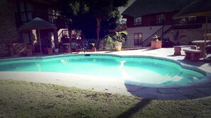 A swimming pool with a stone border, surrounded by a patio area with outdoor furniture and potted plants. - iLanga Lodge (St. Lucia)