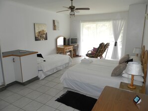 A hotel room with two beds, a desk with a computer, a chair, a ceiling fan, and a window with curtains. - iLanga Lodge (St. Lucia)