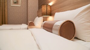 A neatly made bed with white linens and a brown headboard, a bedside lamp, and a framed picture on the wall. - Unique Holiday Hotel (Hualien City)