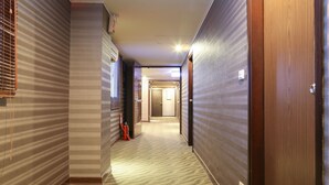 A hotel hallway with striped walls, a fire extinguisher, and a door at the end. - Unique Holiday Hotel (Hualien City)