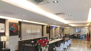 A modern hotel reception area with a long counter, several chairs, and a large decorative vase. - Unique Holiday Hotel (Hualien City)