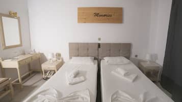 Habitación de hotel con dos camas, un escritorio, una silla y un espejo, y un cartel que dice "Memories".