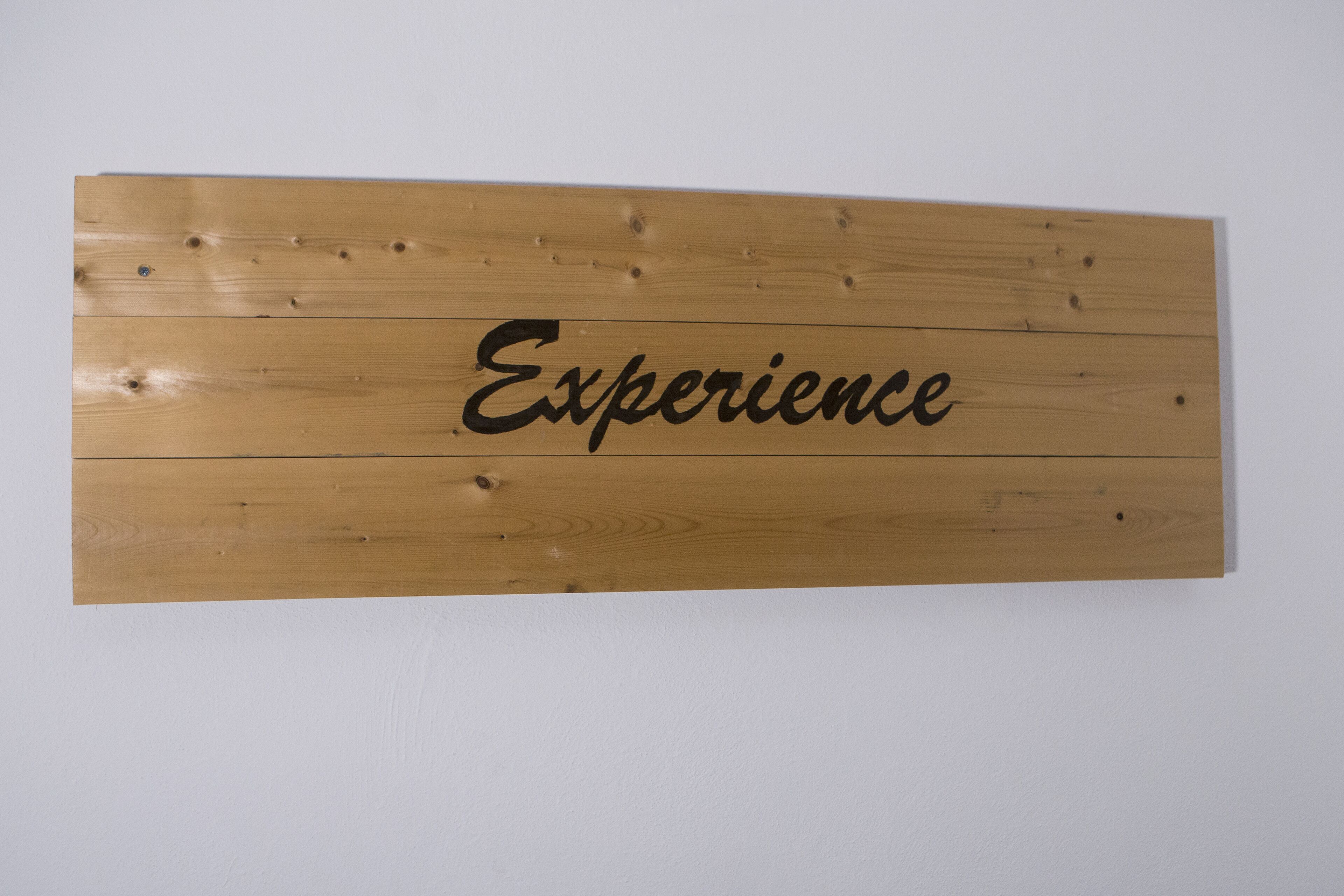 Un cartello di legno con la scritta 'Experience'.