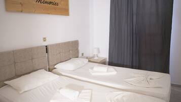 A hotel room with two beds, a wooden headboard, a nightstand with a lamp, and a sign that reads "Memories".