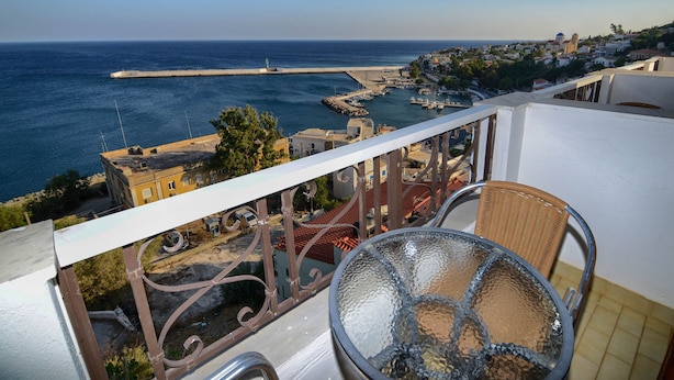 A balcony with a view of a coastal town, a clear sky, and a body of water. - Kastro Hotel (Ikaria)
