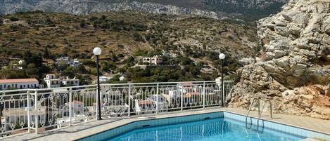 A swimming pool with a view of rocky hills and houses in the background.