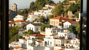 A view from a balcony with a table and chairs, overlooking a densely packed town with various buildings and a church tower. - Kastro Hotel (Ikaria)