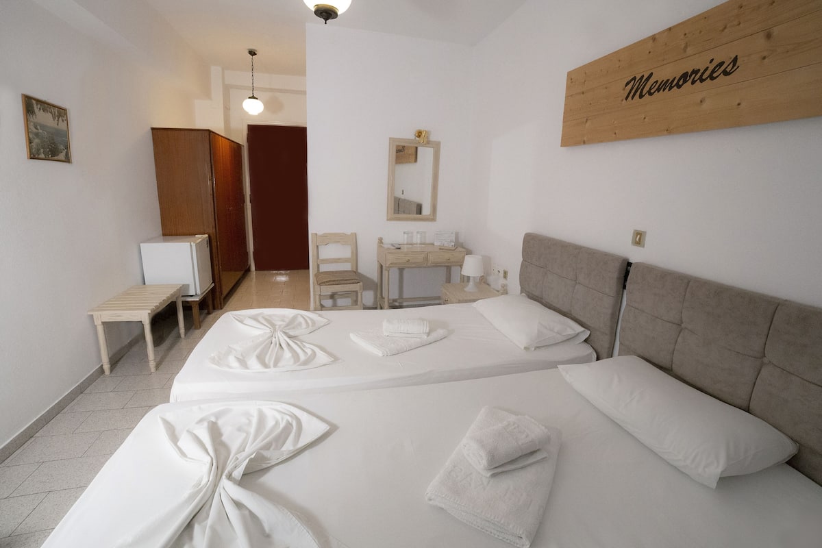 Una habitación de hotel con dos camas, un escritorio, una silla, un tocador y un espejo.