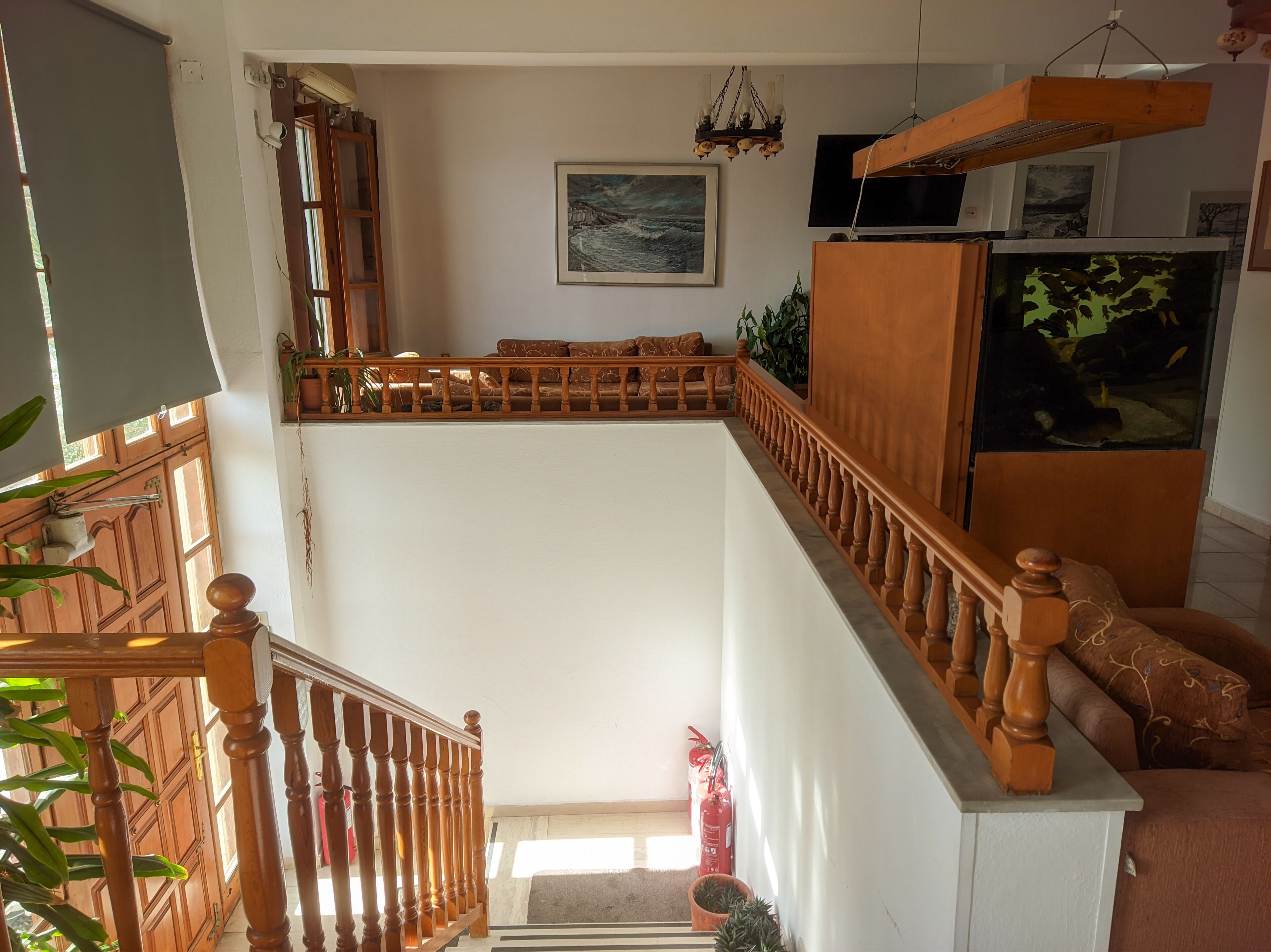 Un escalier avec des balustrades en bois, un extincteur et un tableau accroché au mur.