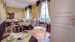 Un espace repas avec plusieurs tables et chaises, une porte portant l’inscription « BAGAGERIE », et une vue sur l’extérieur grâce à de grandes fenêtres.