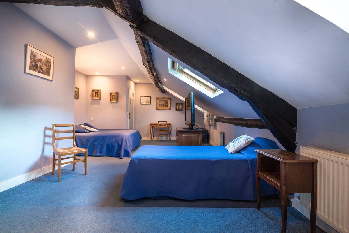 Une chambre avec deux lits, une chaise en bois, une petite table et un radiateur.