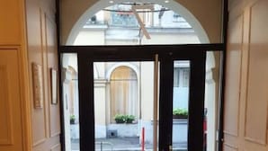 L’entrée d’un hôtel avec un plancher en bois, une porte noire et une vue sur la rue.