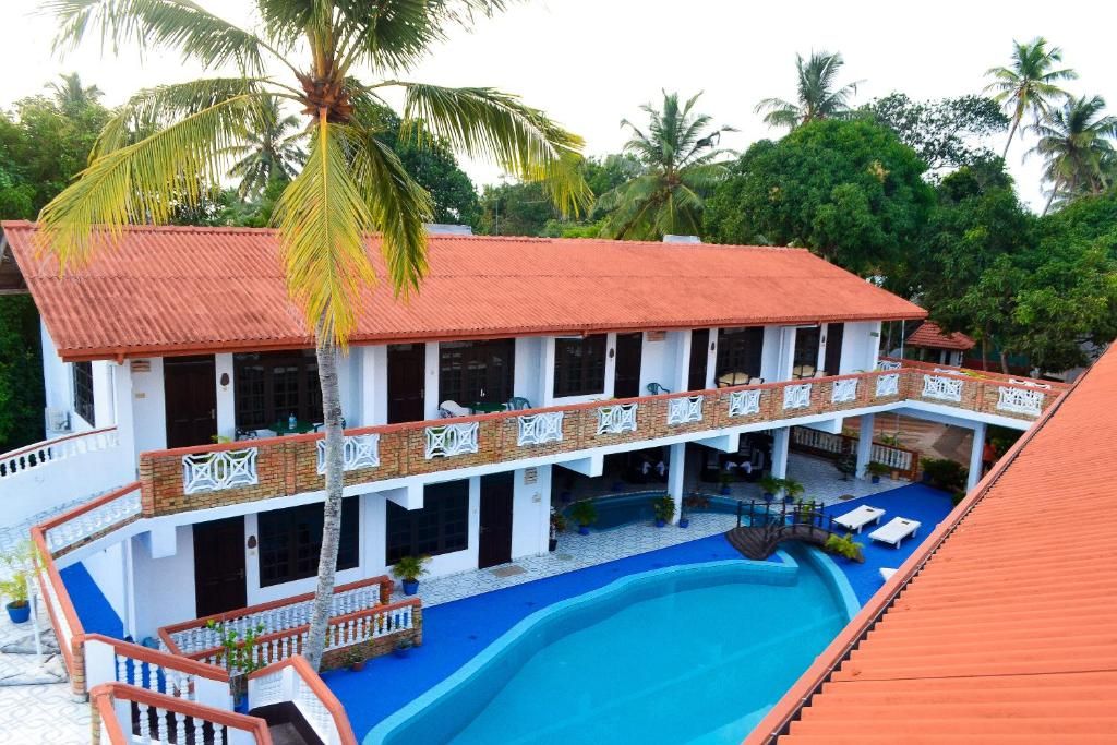 Un bâtiment à deux étages doté d’une piscine, entouré de palmiers.