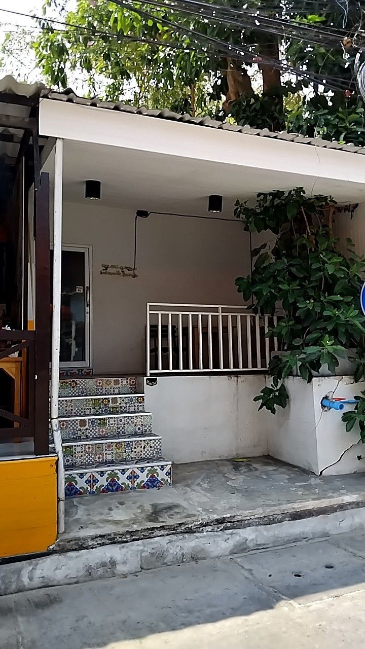 A residential building with a tiled staircase, a white railing, and a door leading to an interior space.