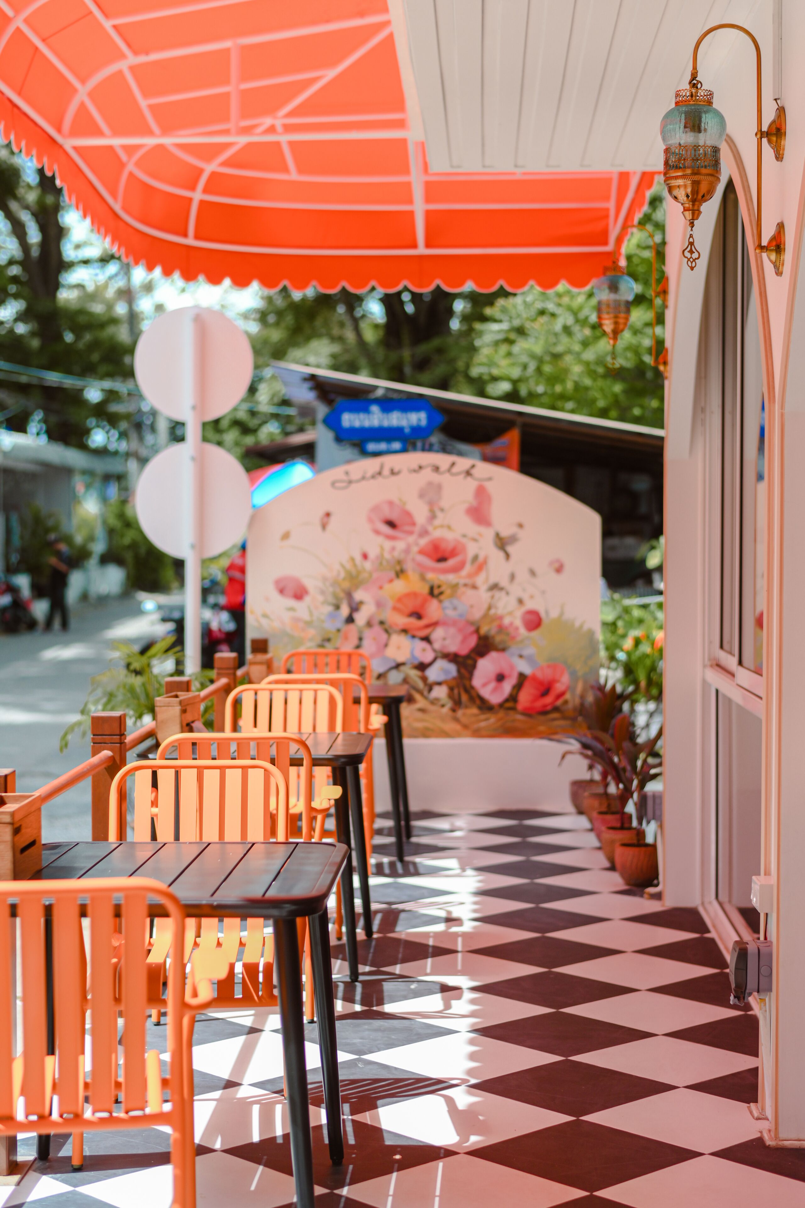 A restaurant with outdoor seating, a checkered floor, and a floral mural.