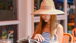 A person reading a magazine at a table with a drink and a plate of food. - Side Walk Boutique Hotel (Rayong)