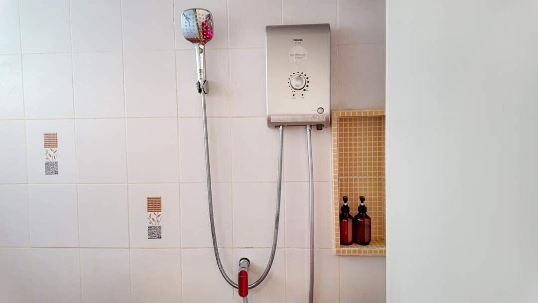 A shower with a handheld showerhead and a wall-mounted control panel.