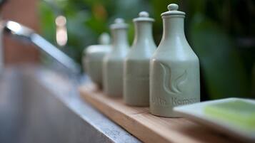 A row of white bottles with a leaf design on a wooden shelf by a sink.