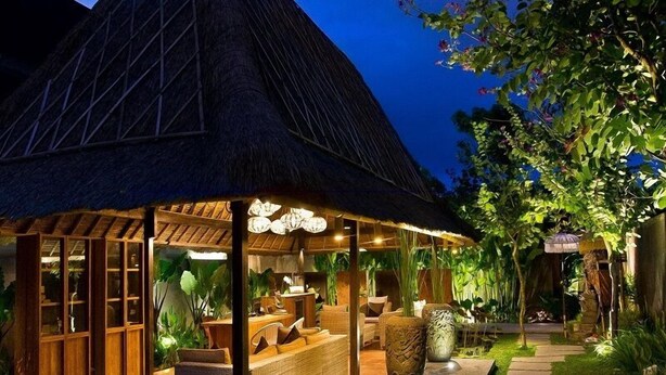 A thatched-roof structure with a bar area, seating, and a water feature. - Komea Villa (Canggu)