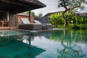 Una piscina con sillas de descanso y una zona de estar cubierta.